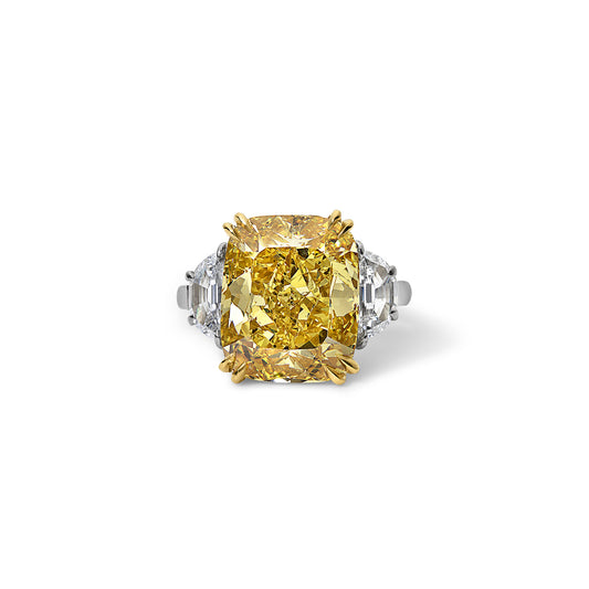 Front view of a stunning 6.80 carat vivid yellow diamond three stone ring with colorless trapezoid cut diamonds, set in handmade platinum and yellow gold.